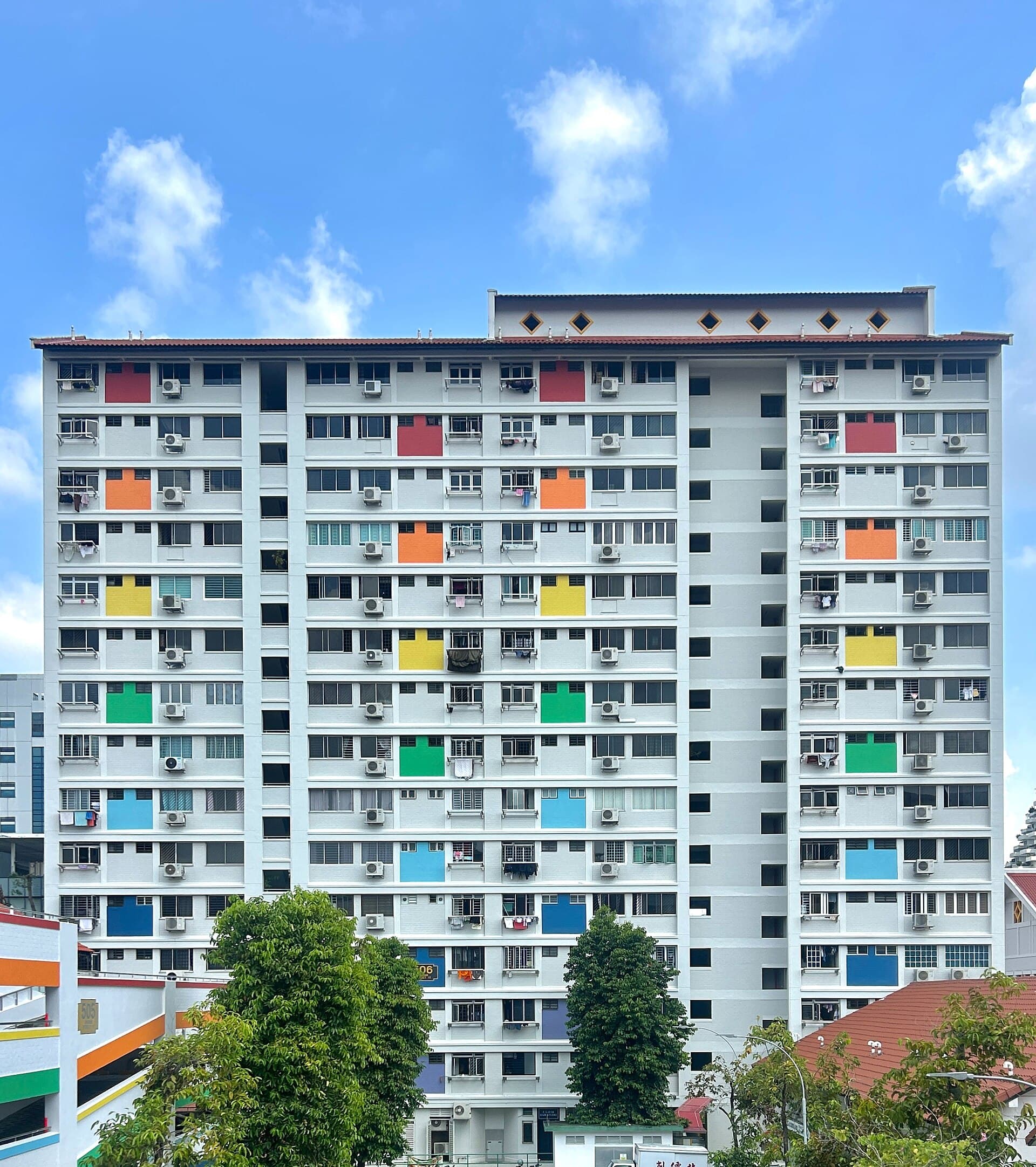 Facade of an HDB apartment block with regular windows, corridor rails and the laundry-pole rhythm of a Singapore heartland estate